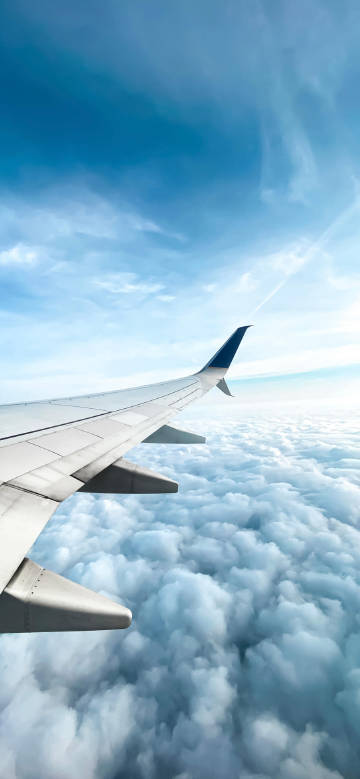 Airplane Wing Soaring Over Puffy White Clouds Wallpaper