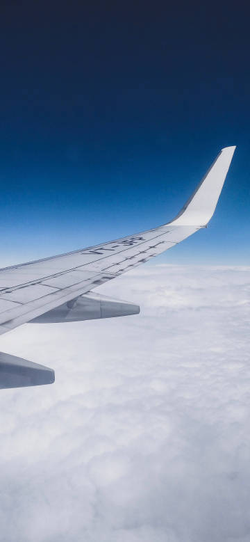 Wing Above the Clouds Under a Clear Blue Sky 4K Phone Wallpaper