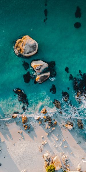 Aerial View of a Serene Beach with Vibrant Blue Water and Stones