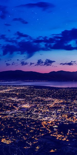 Enchanting Night Cityscape with Crescent Moon and Mountains - Phone Wallpaper