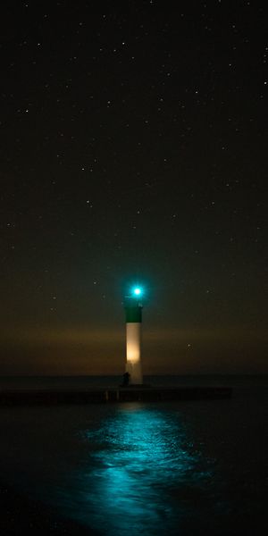 Captivating 4K Phone Wallpaper of a Lighthouse Illuminating the Night Sky