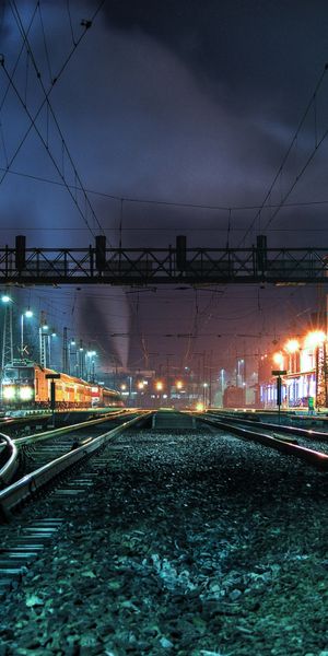 Illuminated Night Railroad with Train Tracks and Urban Landscape