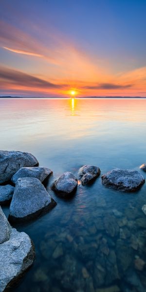 Breathtaking Sunset Over Tranquil Waters with Stones