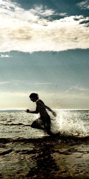 Vibrant beach wallpaper featuring a child running through water, ideal for iPhone