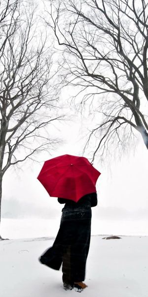Charming Winter Scene: A Person with a Red Umbrella in a Snowy Landscape - 4K iPhone Wallpaper