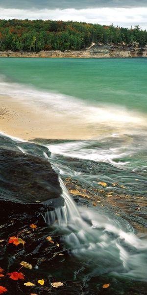 Breathtaking 4K phone wallpaper of a tranquil beach and rocky shoreline