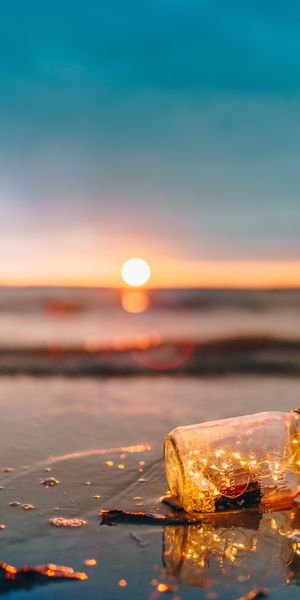 Enchanting mobile wallpaper featuring a glowing jar by the sea at sunset