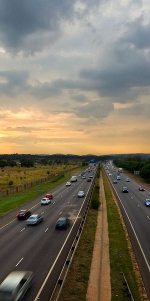 Phone wallpaper: Sunset, Movement, Cities, Sky, Traffic, Road, Cars free download