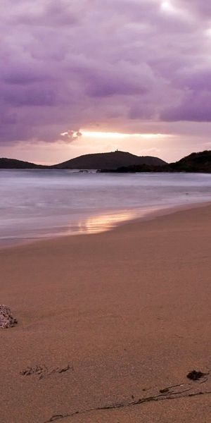 Tranquil evening beach scene with soft waves and purple skies for iPhone background in 4K