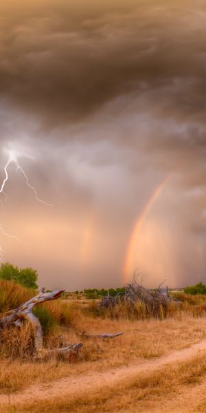 Breathtaking 4K phone wallpaper of a stormy field with rainbow and lightning