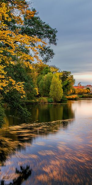 Autumn Landscape with Reflections of Trees and Architecture in Lake