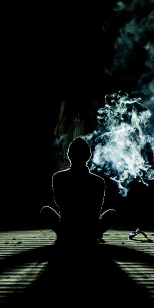 Meditation in the Dark: A Silhouette Surrounded by Smoke