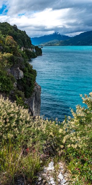 Serene Lake View Surrounded by Mountains and Lush Bushes
