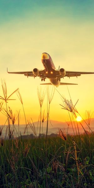 Airplane Taking Off at Sunset Over Grassland