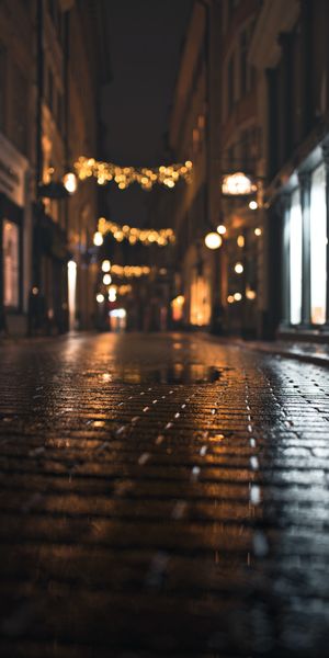 Enchanting Night Street with Wet Paving Stones and Warm Lights