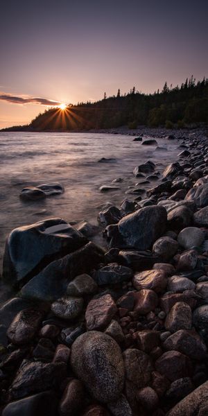 Cool Sunset Over a Serene Lake Shore with Trees and Stones