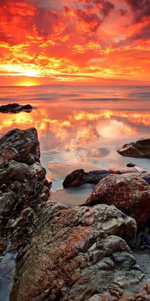 Breathtaking sunset wallpaper featuring a rocky beach and vibrant colors