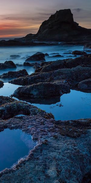 Breathtaking HD phone wallpaper of a beach sunset over rocky shores