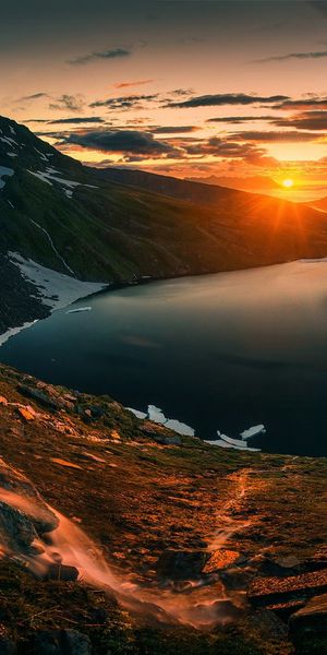 Breathtaking Sunset Over a Tranquil Lake with Waterfall