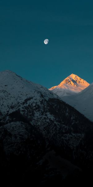 Breathtaking Snow-Covered Mountains at Dusk with Moonlight