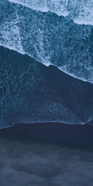 Aerial View of Ocean Waves Crashing on Sandy Shore