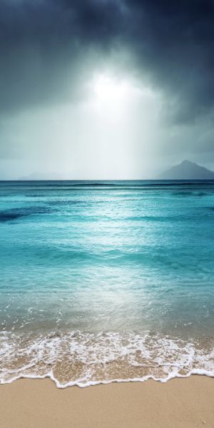 Breathtaking 4K phone wallpaper of a tranquil beach landscape with sea and clouds