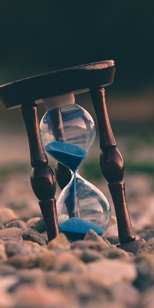 Beautiful Hourglass Set Among Smooth Stones - Perfect for Mobile Wallpaper