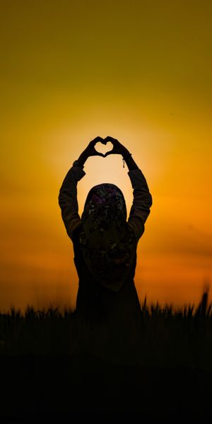 Silhouette of a Girl Holding a Heart at Sunset