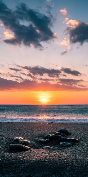 Vibrant Sunset Over the Sea with Shoreline Stones