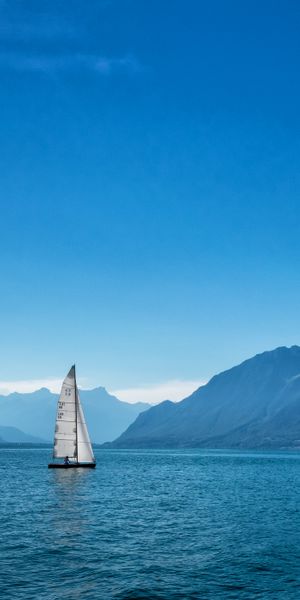 Breathtaking Sailboat on the Serene Sea Surrounded by Mountains