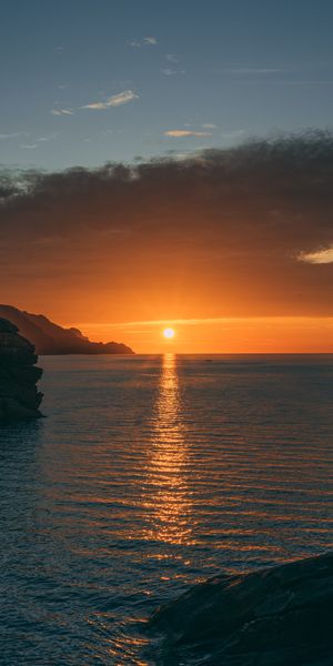 Breathtaking HD wallpaper featuring a sunset over tranquil sea and rocks