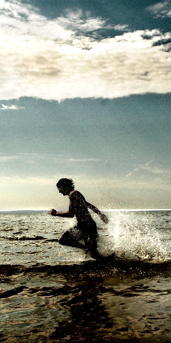 Vibrant beach wallpaper featuring a child running through water, ideal for iPhone
