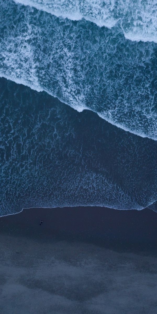 Aerial View of Ocean Waves Crashing on Sandy Shore