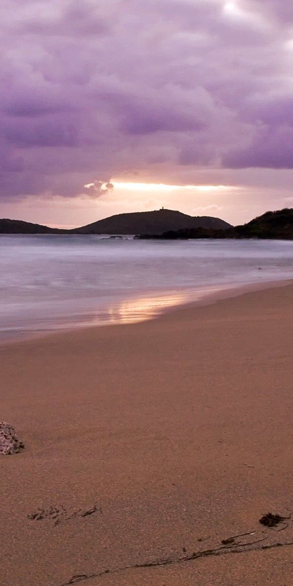 Tranquil evening beach scene with soft waves and purple skies for iPhone background in 4K