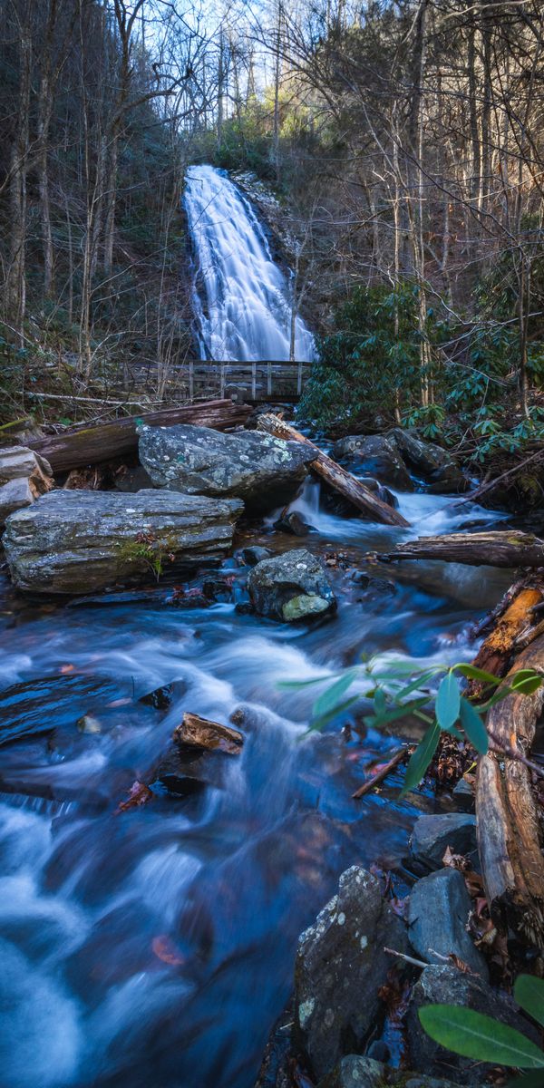 Breathtaking Waterfall Surrounded by Lush Trees and Flowing River