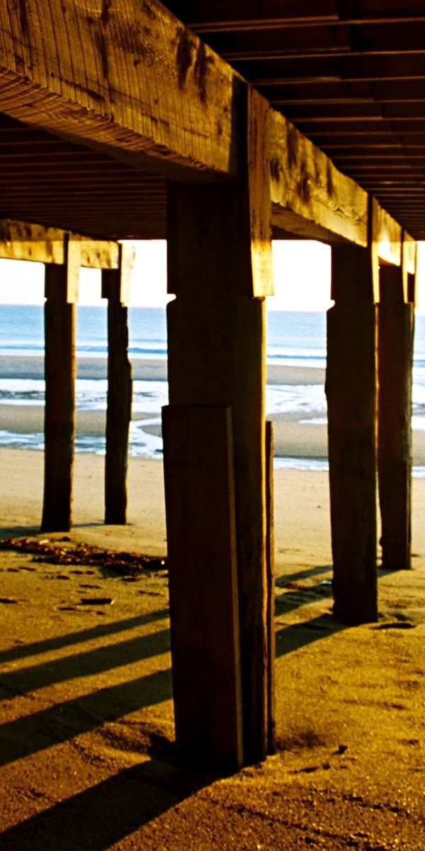 Serene beach wallpaper showcasing ocean waves beneath a wooden pier