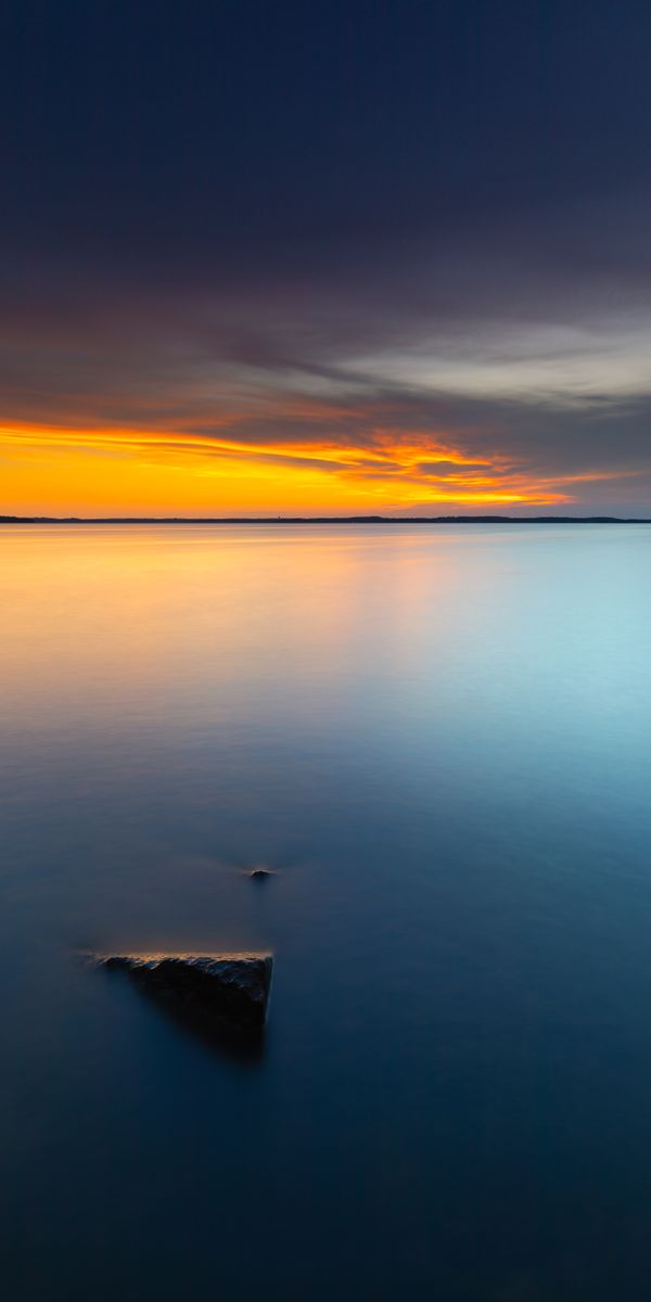 Serene Sunset Over the Tranquil Sea with a Unique Rock