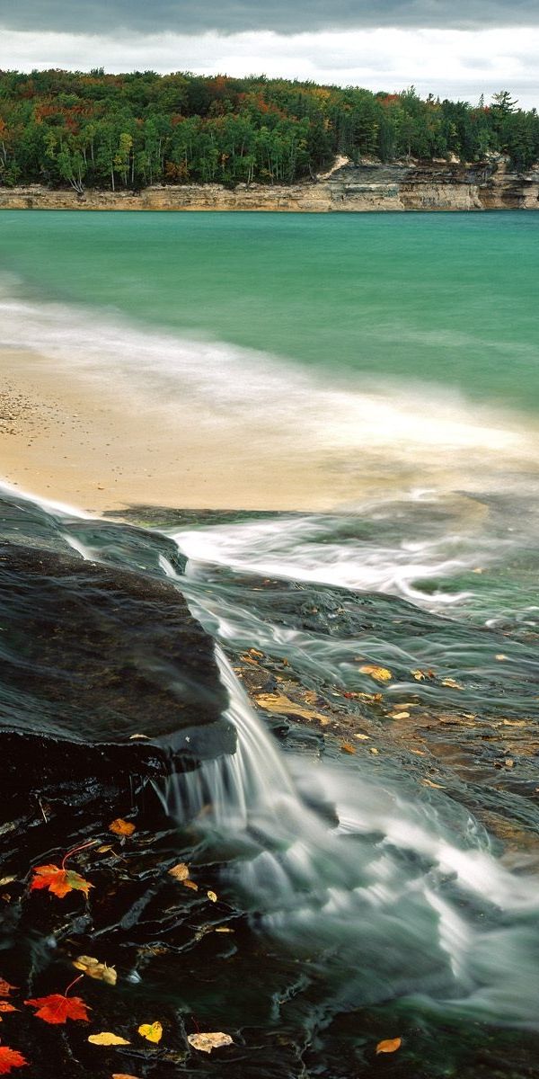 Breathtaking 4K phone wallpaper of a tranquil beach and rocky shoreline
