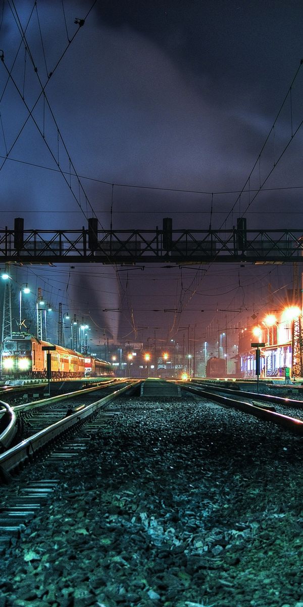 Illuminated Night Railroad with Train Tracks and Urban Landscape