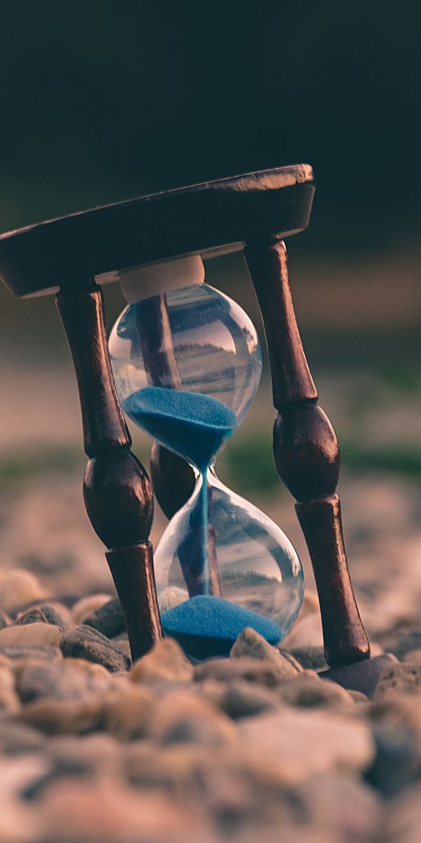 Beautiful Hourglass Set Among Smooth Stones - Perfect for Mobile Wallpaper